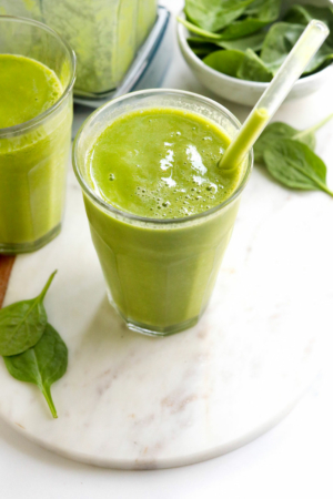 green smoothie in glass with straw