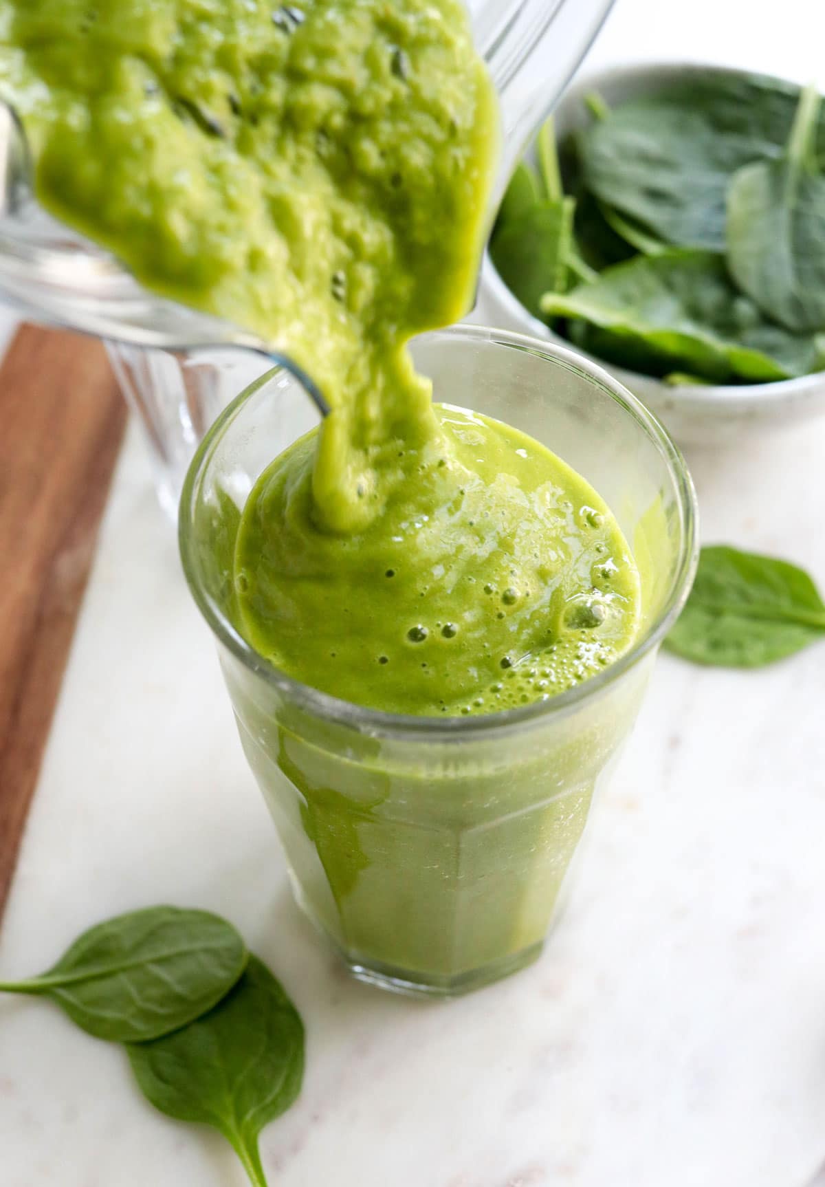 green smoothie poured into a glass from the blender