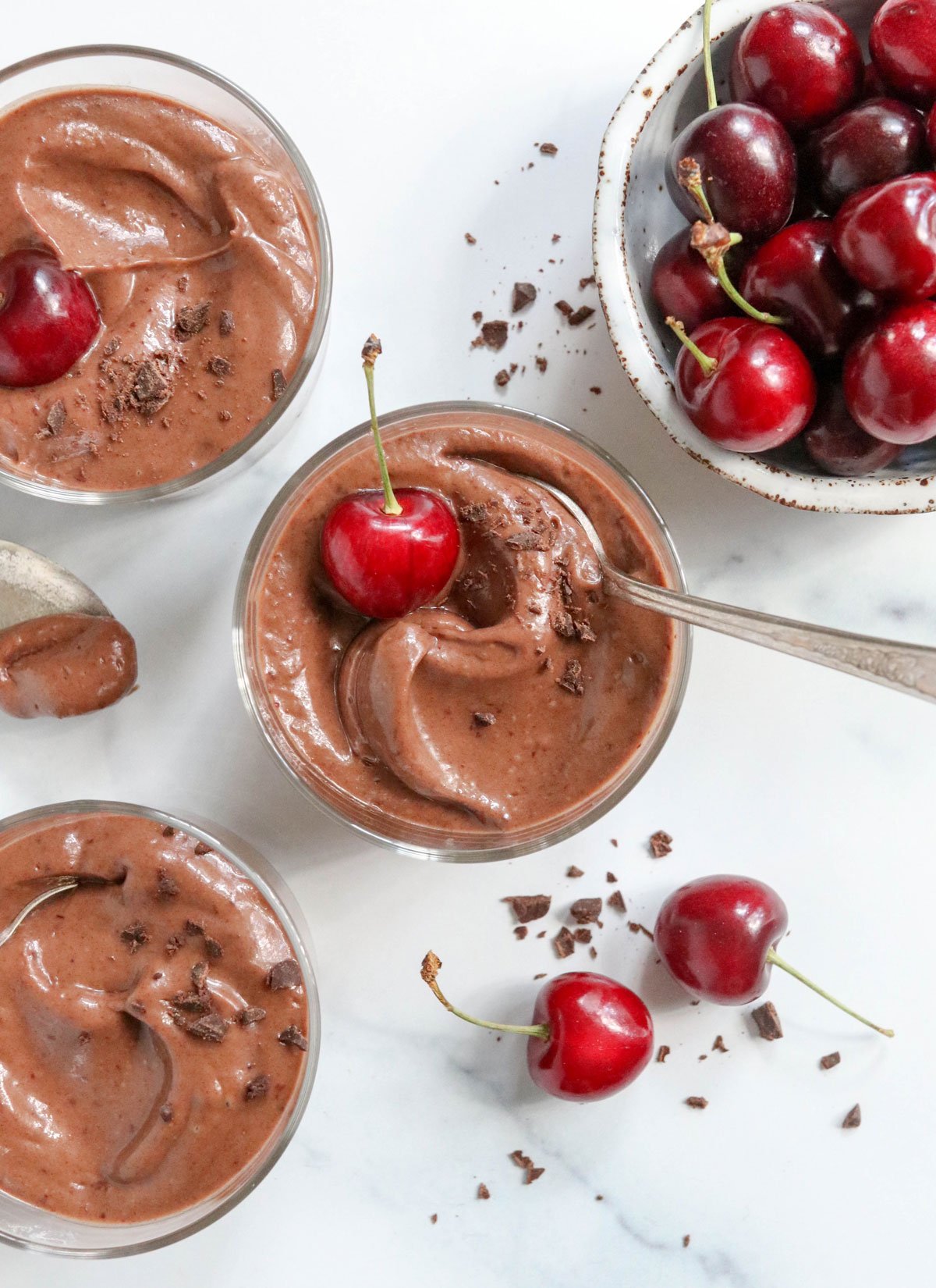 3 cups of chocolate pudding with cherries on top