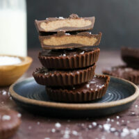 almond butter cups stacked on dark plate.