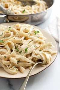 vegan alfredo pasta on plate with fork