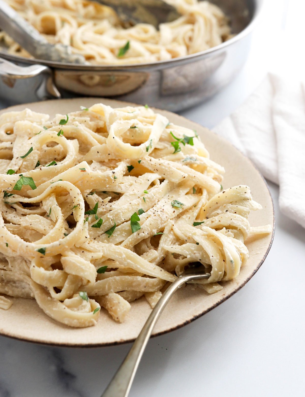 vegan alfredo pasta on plate with fork