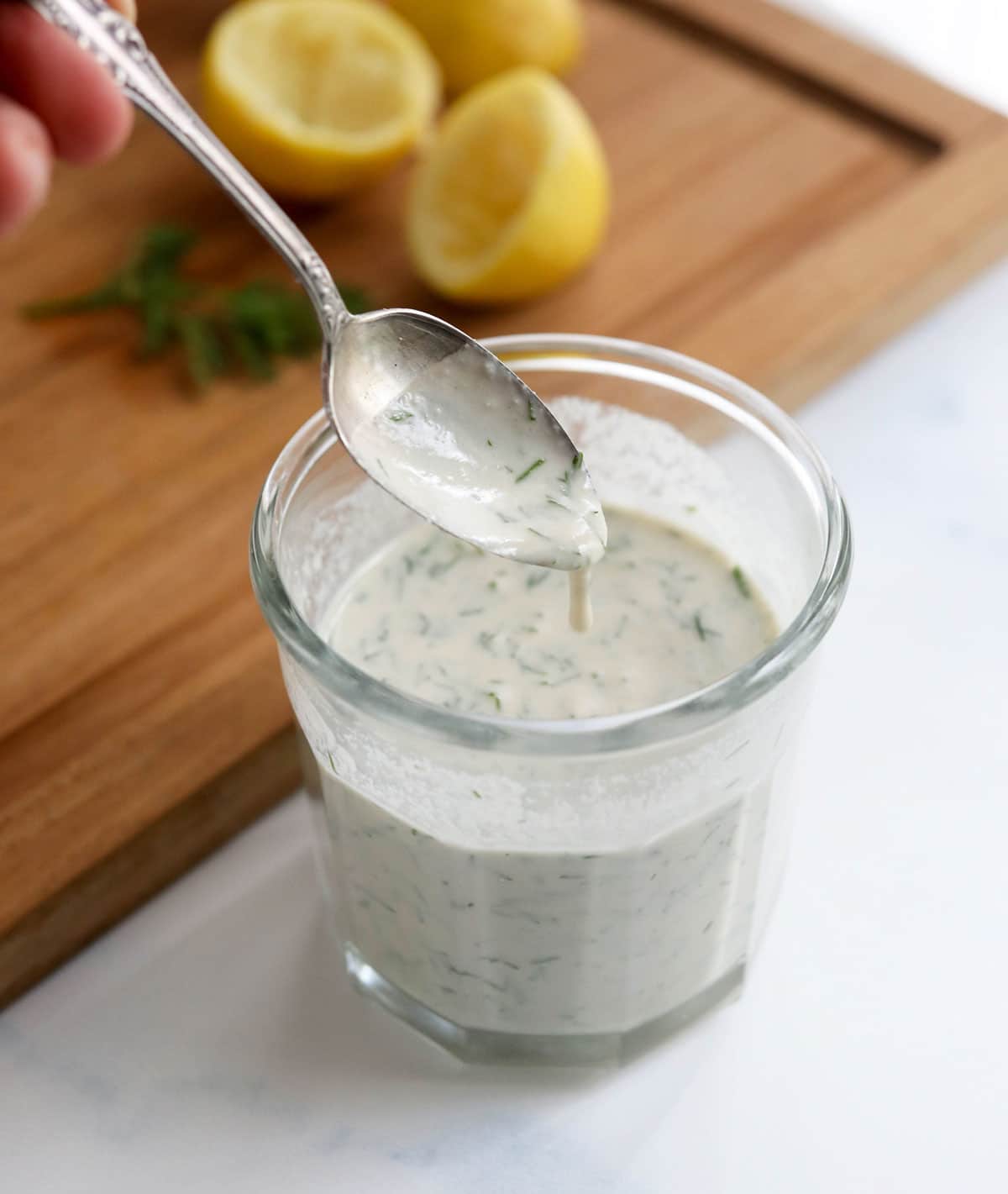 creamy tahini dill dressing dripping off spoon