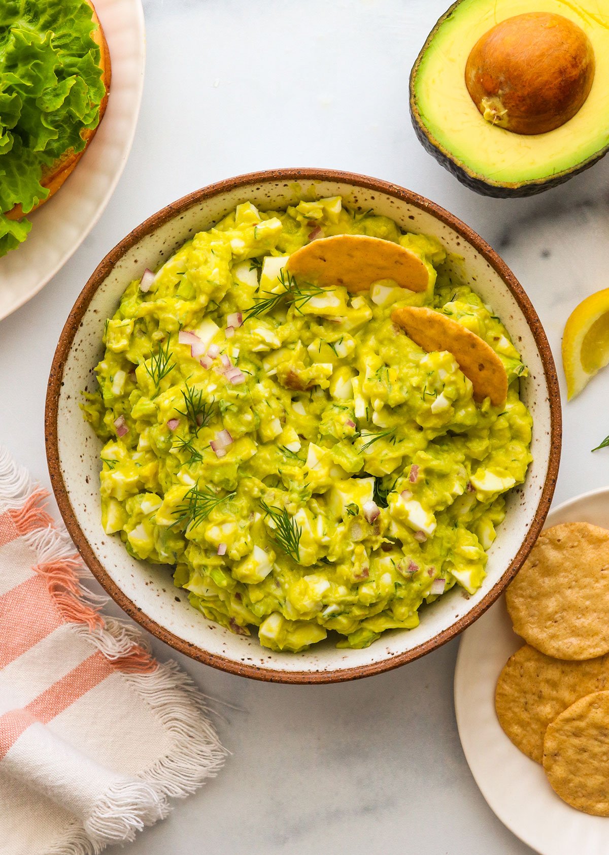 avocado egg salad served in a bowl with crackers. 