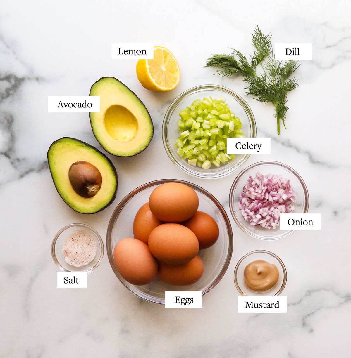 avocado egg salad ingredients labeled on a marble surface.