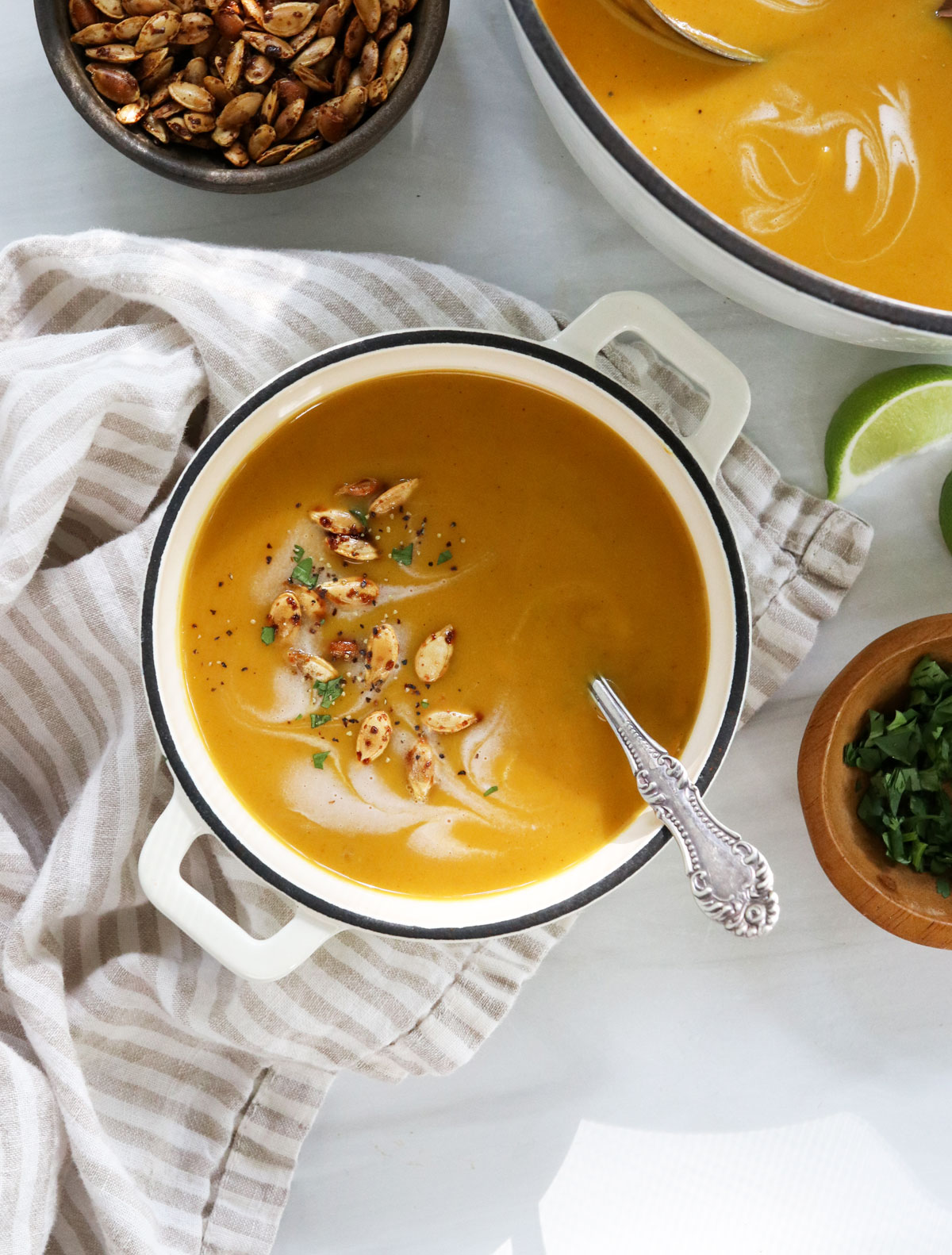 butternut soup served in white bowl with roasted seeds.