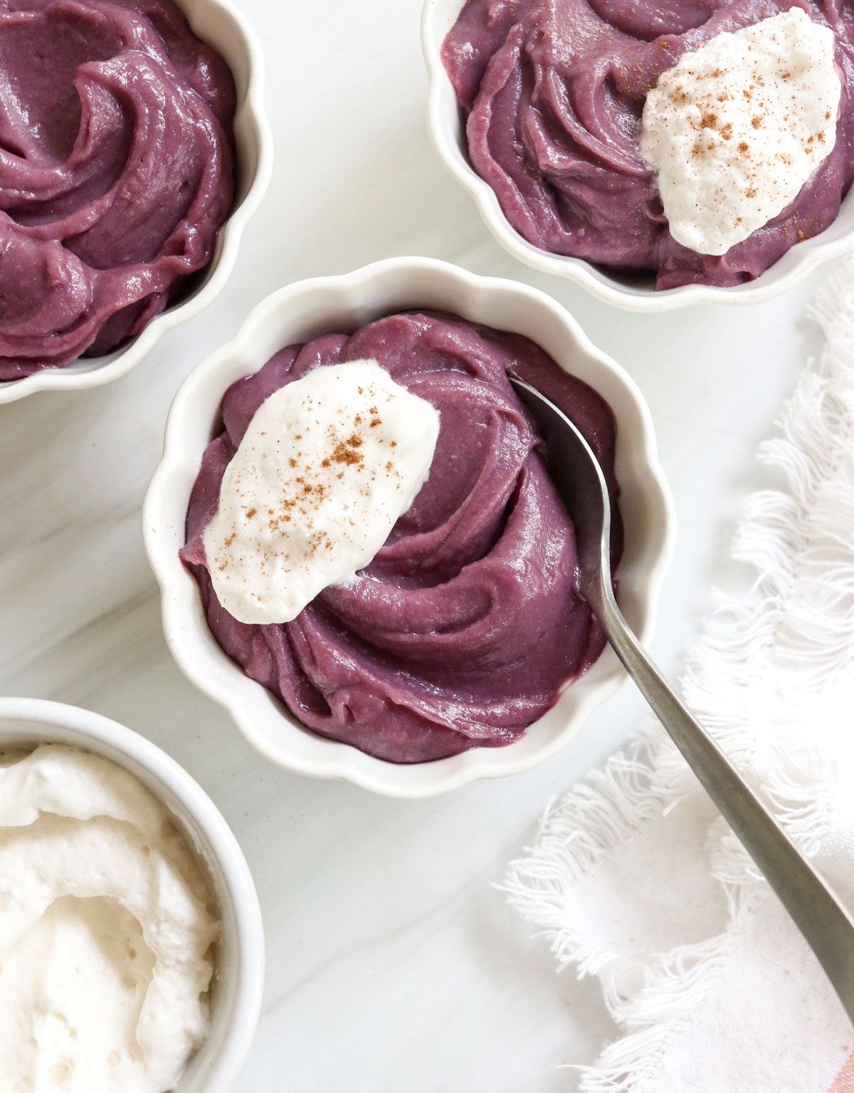 3 bowls of sweet potato pudding with spoon inside.