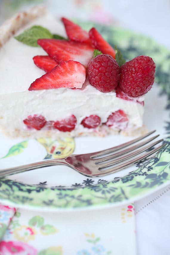 slice of coconut cream pie on a plate with strawberry slices and raspberries on top