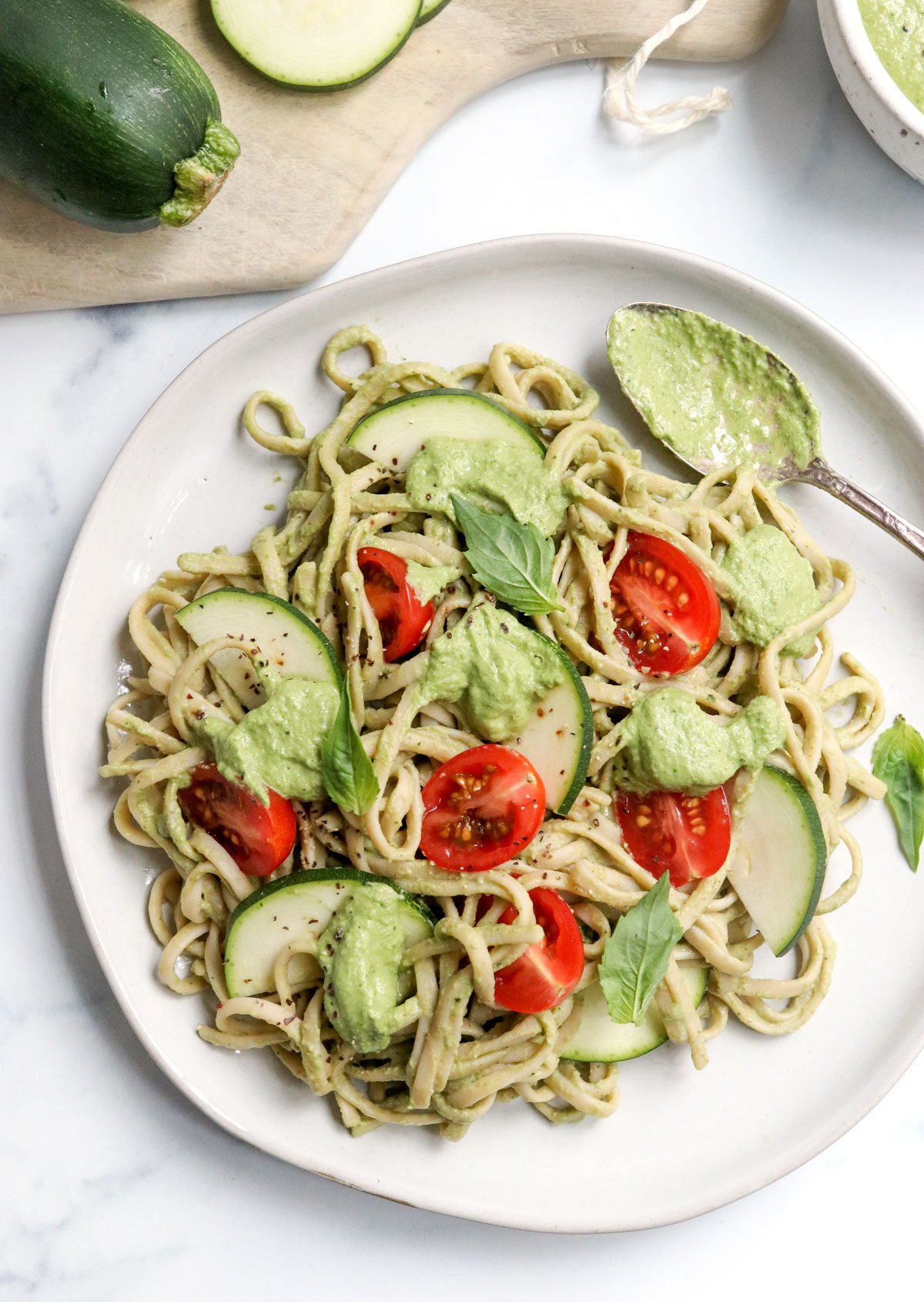zucchini pesto served on pasta with sliced cherry tomatoes.