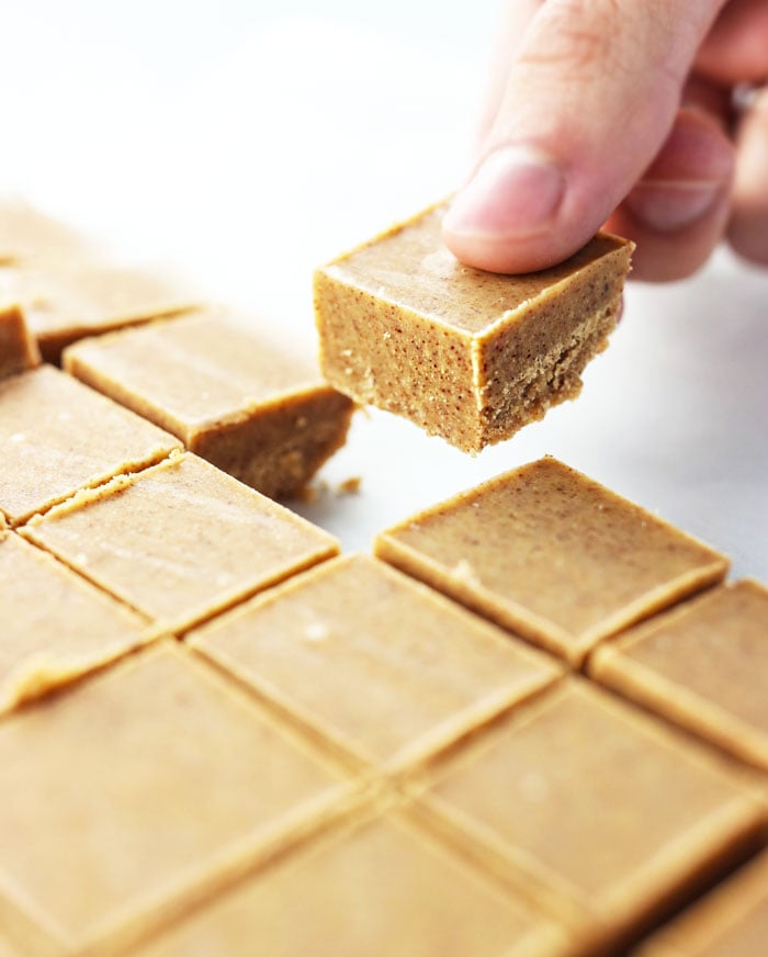 hand picking up an almond butter fudge slice