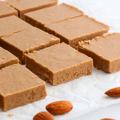 almond butter fudge sliced into squares on parchment paper.