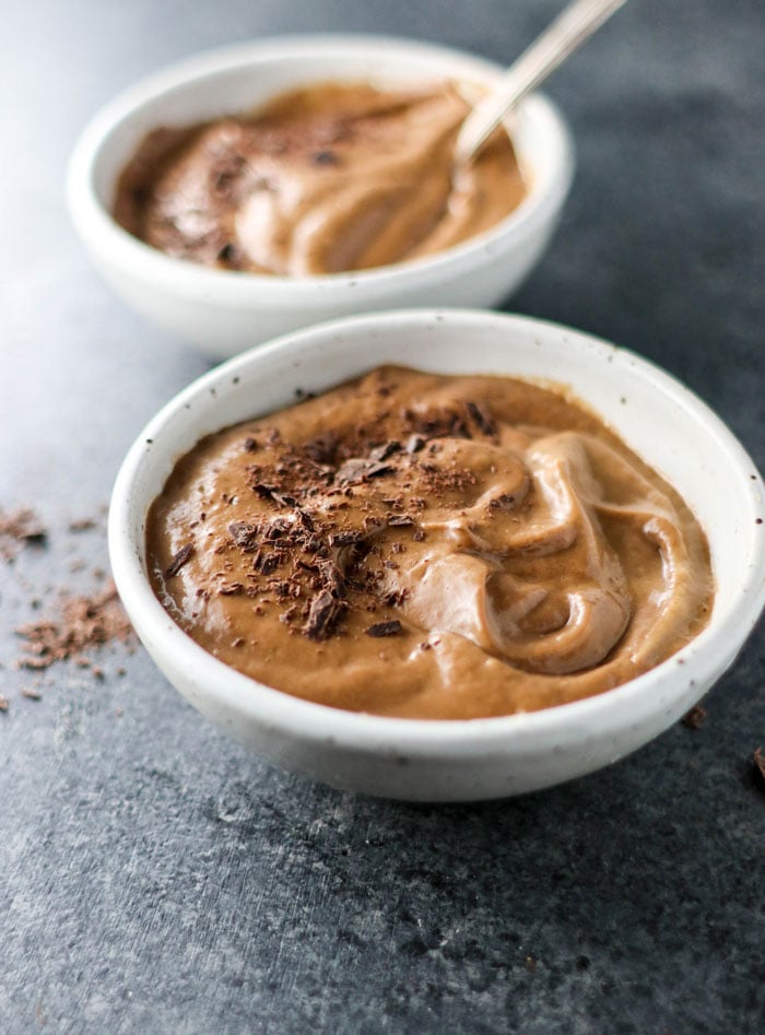 two bowls of chocolate avocado pudding with chocolate shavings on top