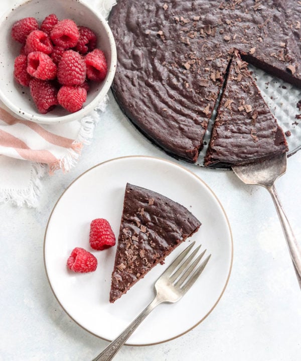 flourless chocolate cake slice on plate with raspberries