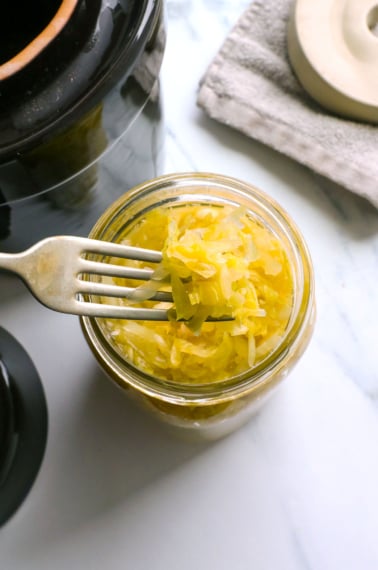 homemade sauerkraut lifted on a fork from a jar.