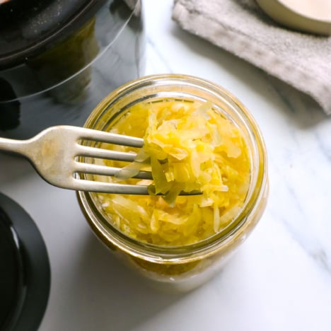 homemade sauerkraut lifted on a fork from a jar.