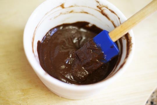 stirring melted chocolate in a small white bowl with a spatula