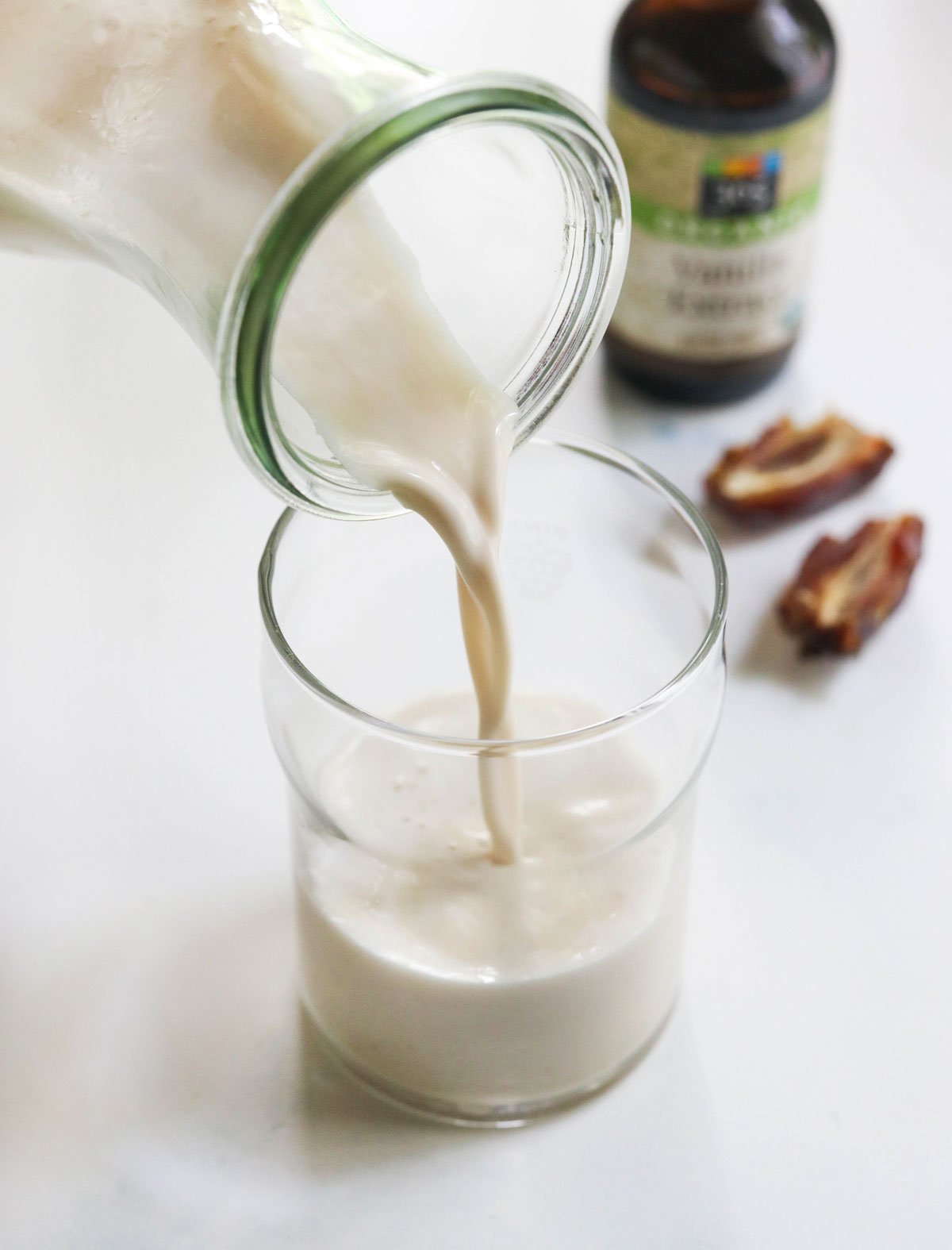 vanilla almond milk poured into glass with dates in background