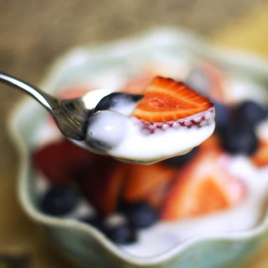 spoonful of coconut cream pudding with blueberries and strawberries