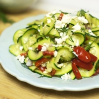 Mediterranean zucchini pasta salad topped with dill and cheese