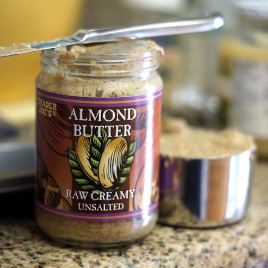 jar of almond butter scooped into a measuring cup