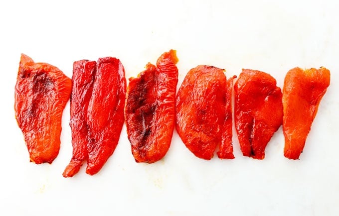 skinned roasted red peppers in a line