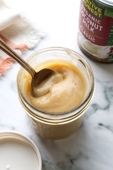 homemade sweetened condensed coconut milk in a jar with a spoon.