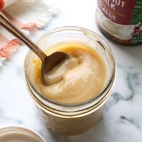 homemade sweetened condensed coconut milk in a jar with a spoon.
