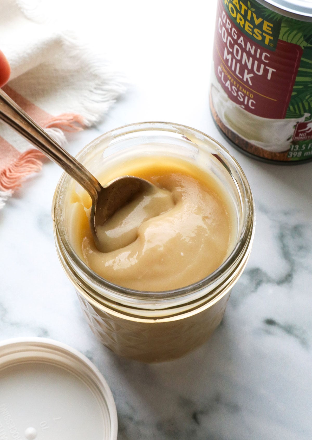 homemade sweetened condensed coconut milk in a jar with a spoon.