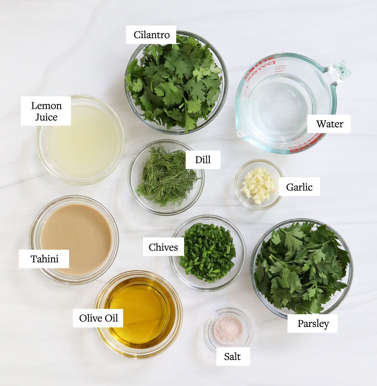 green goddess dressing ingredients labeled in glass bowls.