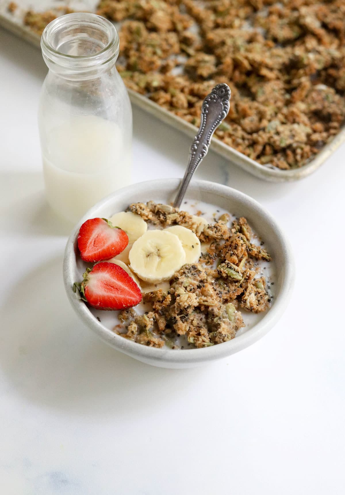 pumpkin seed granola in a bowl with jar of milk