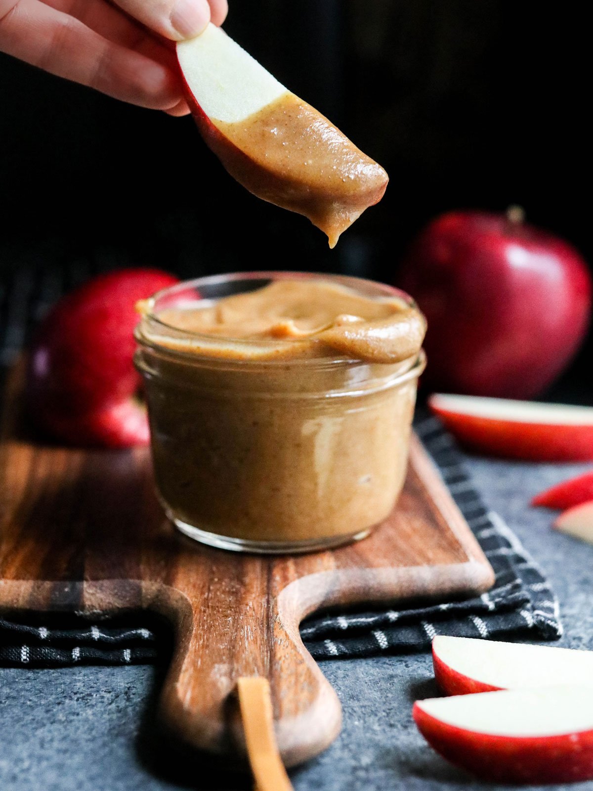 apple dipped in date caramel with dark background.