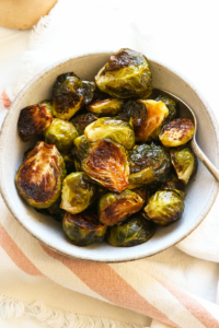 balsamic roasted brussels sprouts served with a spoon in a white bowl.