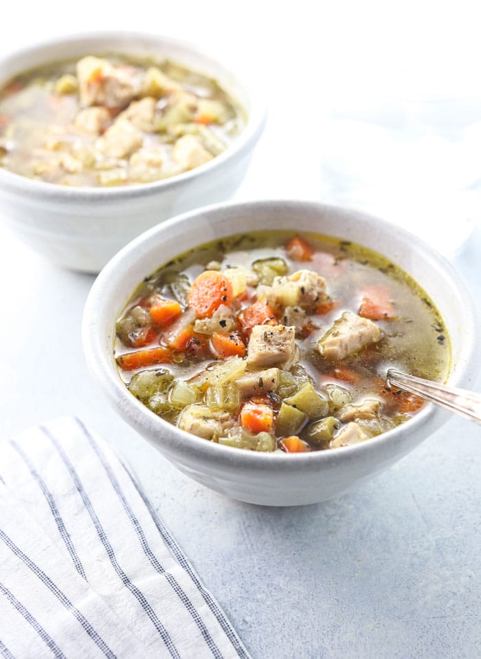 two bowls of chicken and vegetable soup with spoon 