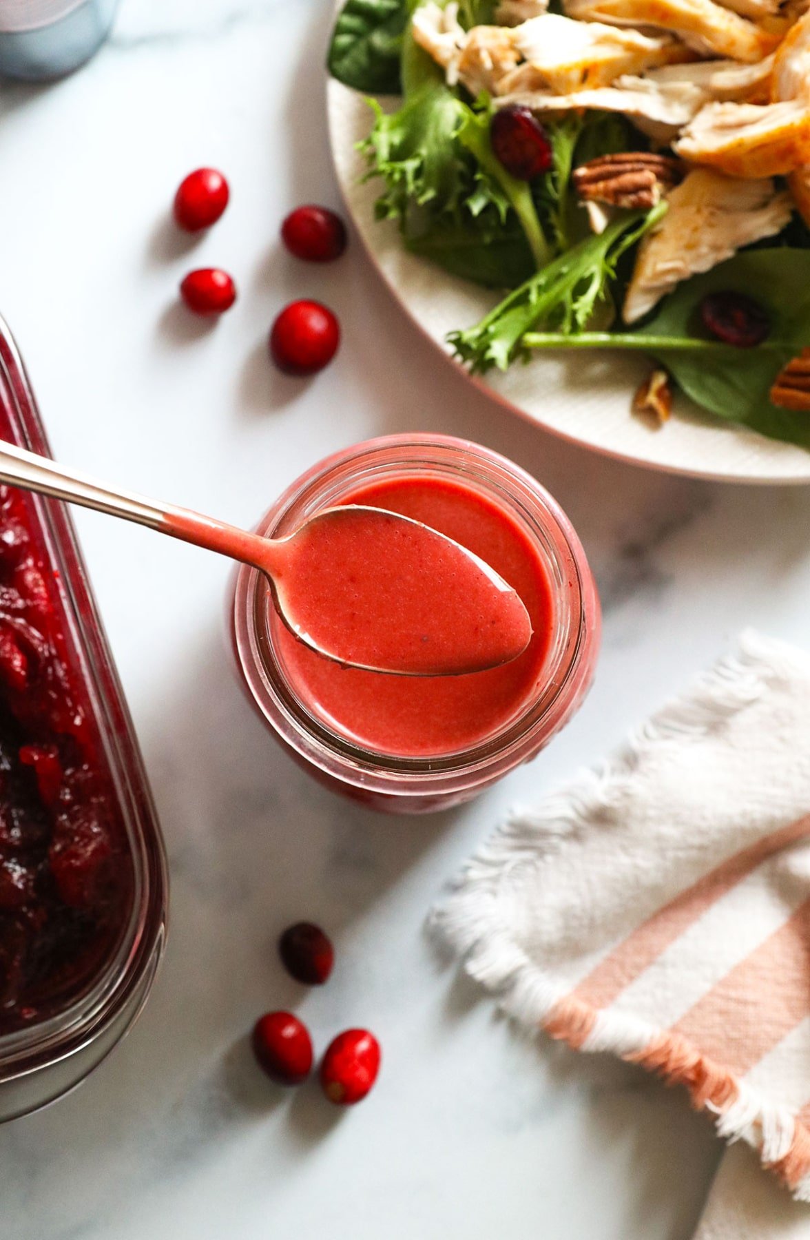 cranberry vinaigrette on a spoon over a jar of dressing.