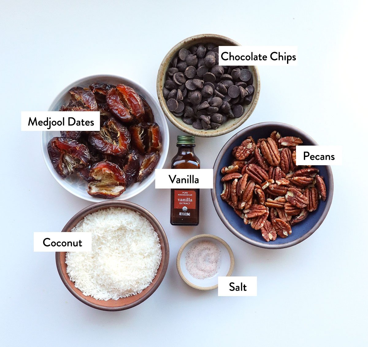 dates, pecans, coconut, vanilla, and salt labeled in bowls. 