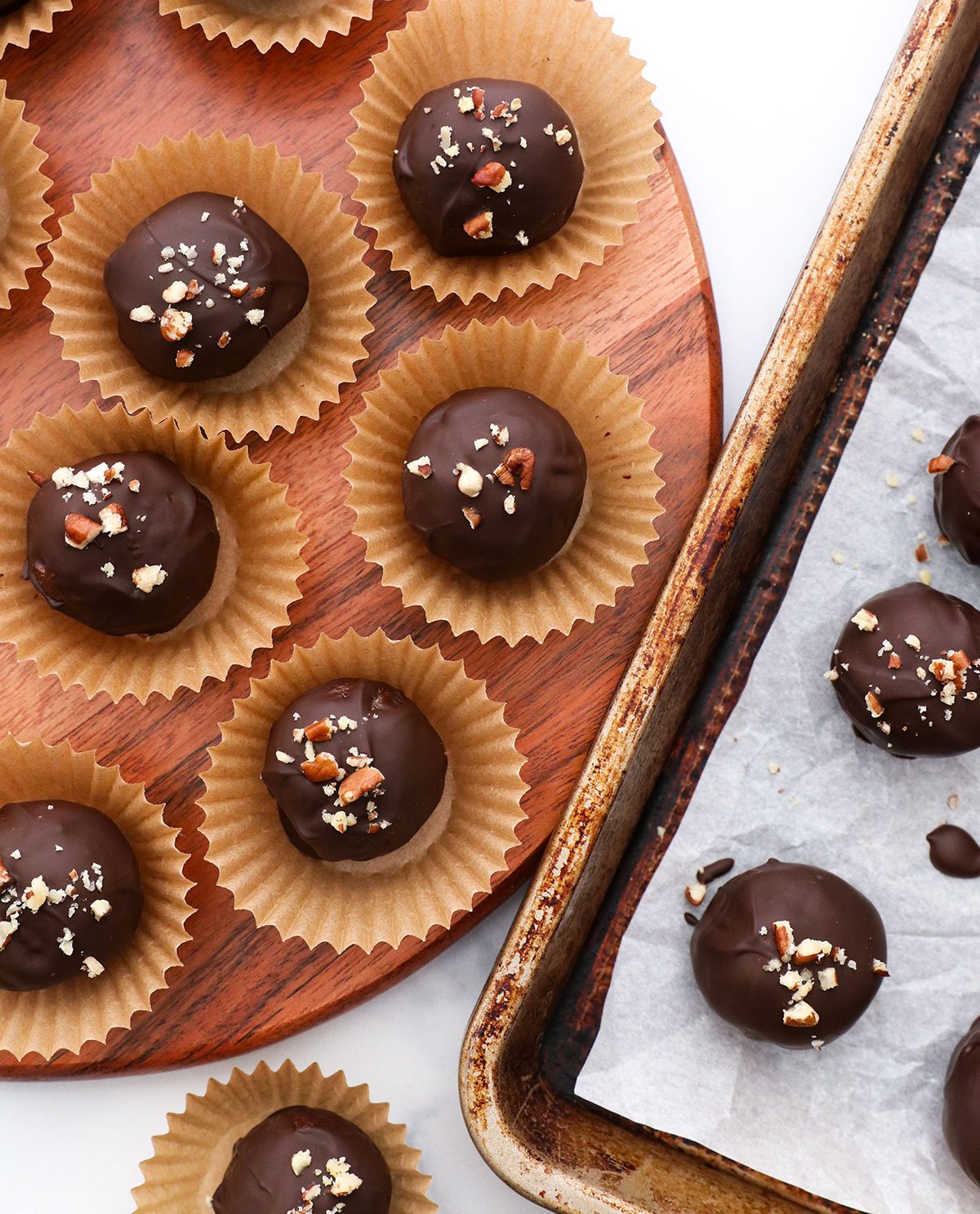 pecan pie truffles coated in chocolate and served on a wooden board. 