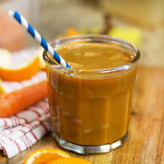 glass of carrot-ginger juice with a straw