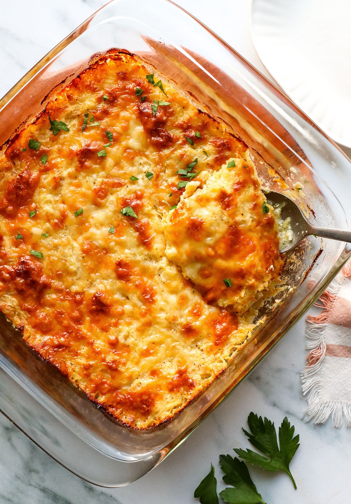 spoon scooping spaghetti squash casserole out of a square pan. 
