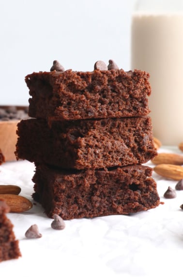 almond pulp brownies stacked on white parchment.
