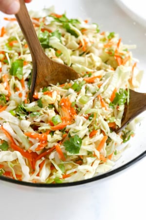 cabbage salad in bowl with tongs