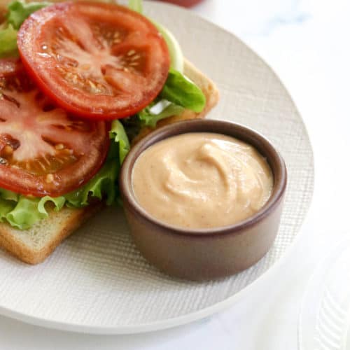 vegan sriracha mayo in a small brown bowl by a sandwich