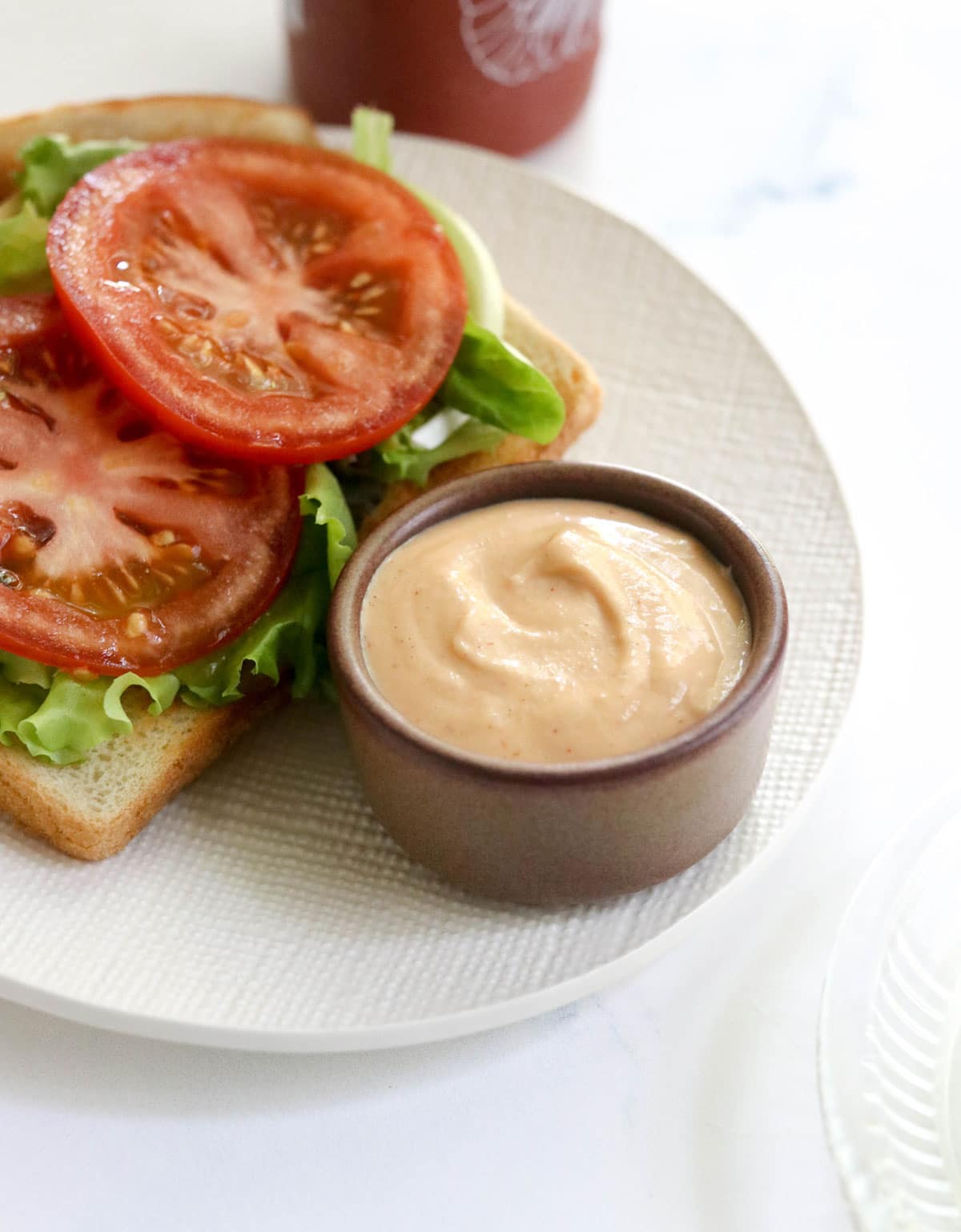 vegan sriracha mayo in a small brown bowl by a sandwich