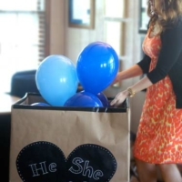 Gender reveal party with mom opening box of blue balloons