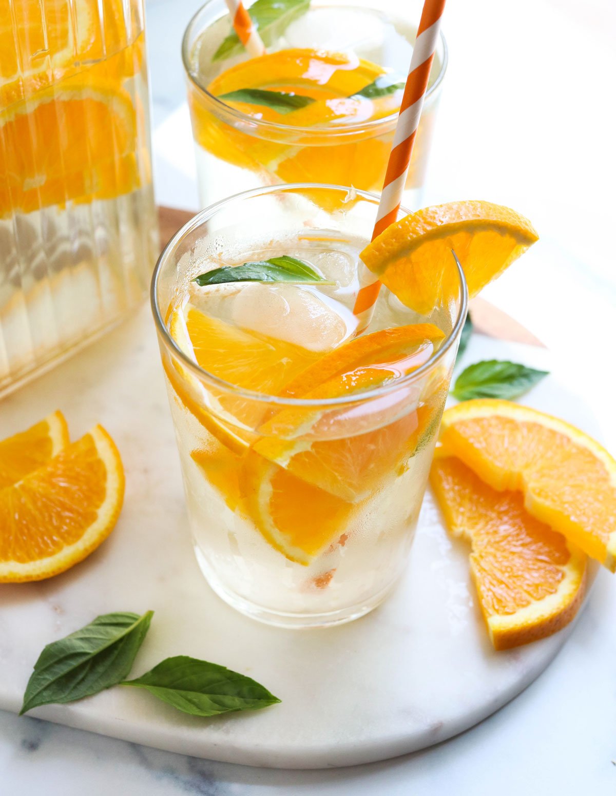 orange infused water with extra orange slices on marble