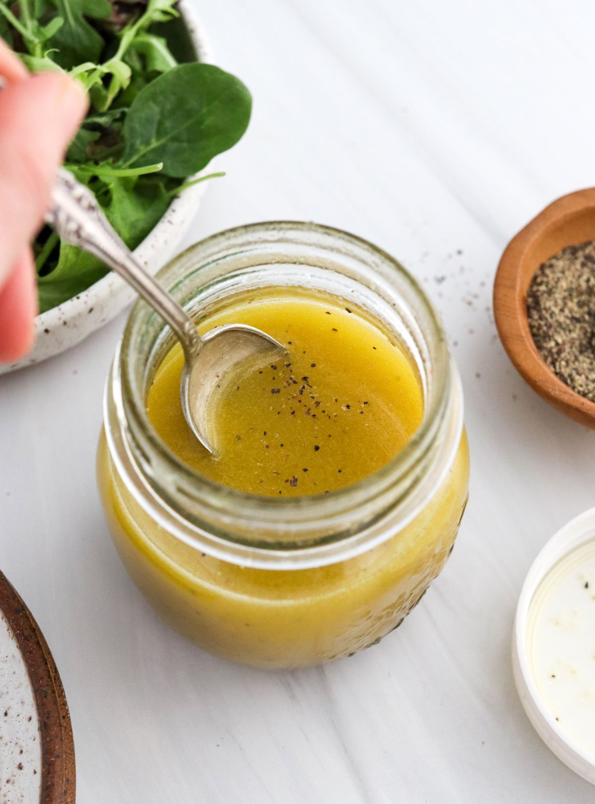 spoon added to jar of apple cider dressing
