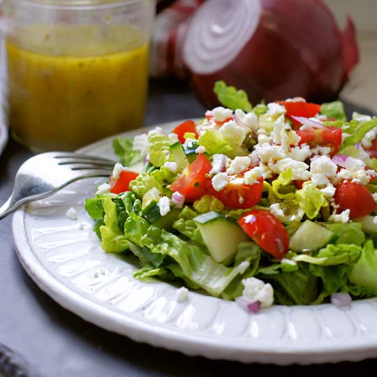 salad on a plate with dressing in a jar on the side