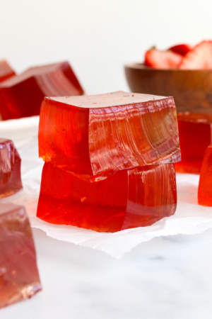 homemade jello squares stacked on parchment paper.