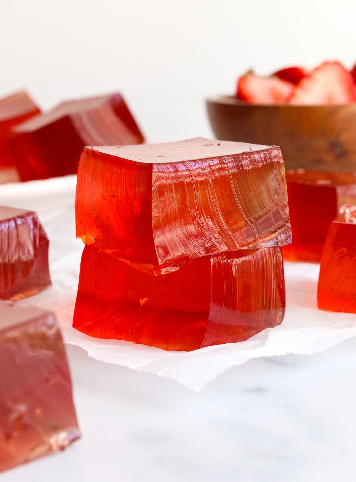 homemade jello squares stacked on parchment paper.