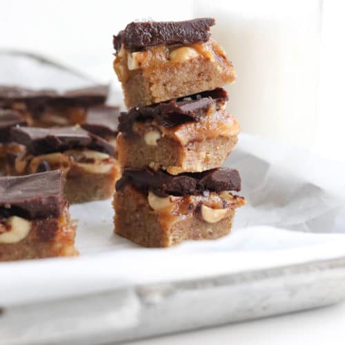 homemade snickers bars stacked on a pan