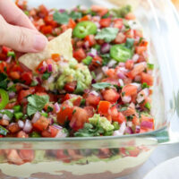 chip dipped into a dish of vegan 7 layer dip.